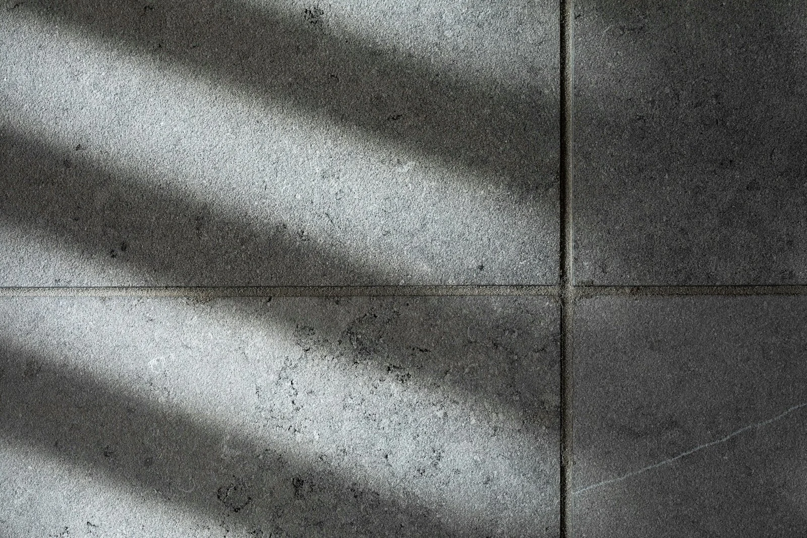 Grå klinkerplattor i stort format med solljus som faller snett över golvet